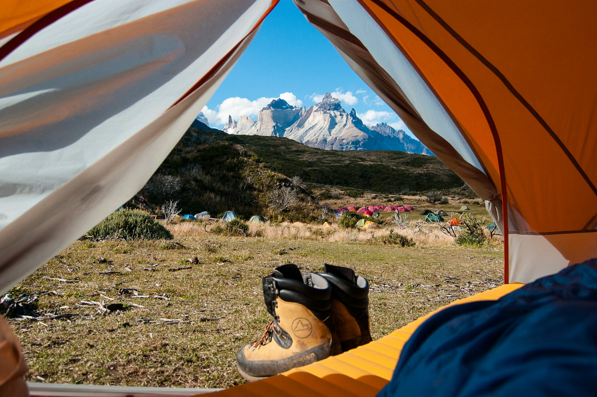 person in red and black shorts sitting on orange and white tent during daytime